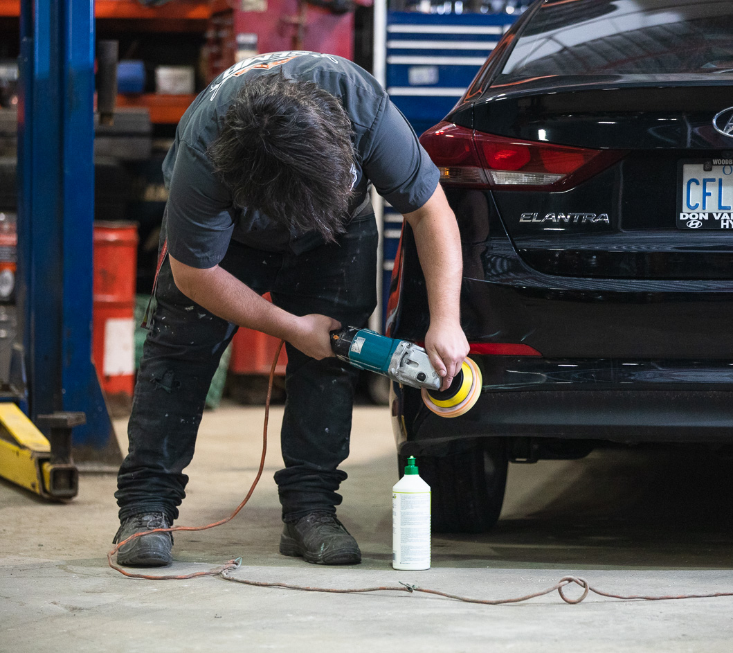 A man polishing the bumper of a car.